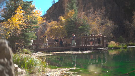 Tourists-visit-Hanging-Lake-boardwalk,-Colorado-during-fall,-low-angle-pan