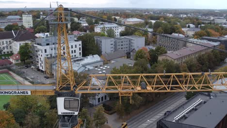 drone-shot-of-new-Riia-kvartal-district-building-processes,-close-up-of-yellow-construction-crane-pan-shot-from-left-to-right