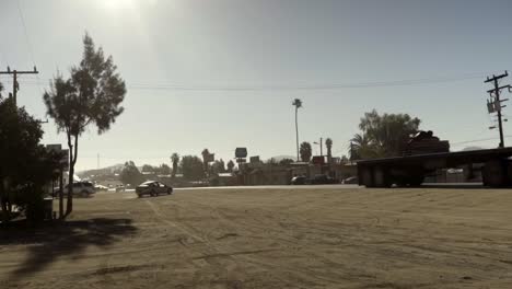 Zeitlupe-Eines-Großen-Lastwagens,-Der-Auf-Einer-Staubigen-Straße-Durch-Eine-Kleine-Stadt-In-Baja-California-Vorbeifährt