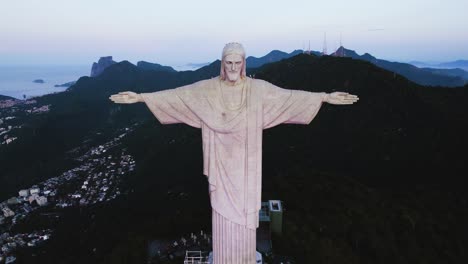 Aerial-view-of-the-sunlit-Cristo-Redentor-statue-on-top-of-the-Corcovado-Mountain-in-Rio,-Brazil---pull-back,-drone-shot
