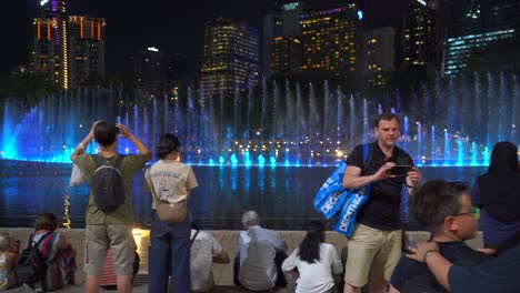 Slow-pan-across-tourists-gathered-at-famous-water-and-light-show-in-Kuala-Lumpur