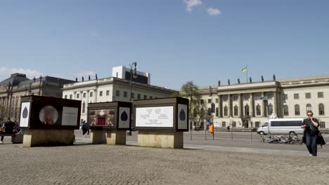 Traffic-And-People-Going-Past-View-Of-Humboldt-University-of-Berlin-On-Sunny-Day-With-Blue-Skies-Viewed-From-Bebelplatz-Square