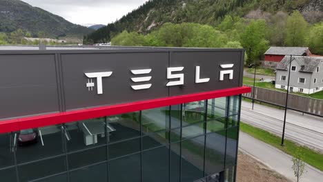 Tesla-car-dealership-in-Forde-Norway---Closeup-moving-backwards-from-big-Tesla-logo-on-wall-of-shop