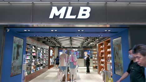 Chinese-pedestrians-walk-past-the-American-professional-baseball-organization,-Major-League-Baseball-,-official-merchandise-store