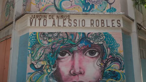 Graffiti-Mit-Gesichtern-Und-Organischen-Formen-In-Blau--Und-Gelbtönen,-Gemalt-An-Der-Ecke-Des-Vito-Alessio-Robles-Kindergartens-Im-Roma-Viertel,-Mexiko-Stadt
