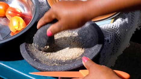 Close-up-of-woman's-hands-using-a-mortar-and-pestle-grinding-seeds-and-herbs-for-lunch-preparation