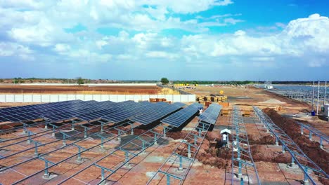 beautiful-landscape-view-with-dramatic-clouds,-Laborers-are-picking-up-the-solar-panels-and-modules-that-will-be-fitted-at-solar-power-station-located-in-India