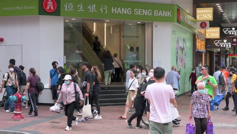 Chinesische-Fußgänger-Gehen-An-Dem-In-Hongkong-Ansässigen-Bank--Und-Finanzdienstleistungsunternehmen-Und-Dem-Hauptindikator-Für-Den-Hongkonger-Aktienmarkt,-Der-Hang-Seng-Bank-Und-Einer-Filiale-In-Hongkong-Vorbei
