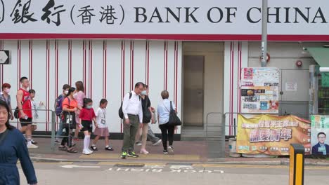 Pedestrians-walk-through-a-zebra-crossing-in-front-of-the-Chinese-state-owned-commercial-banking-company,-Bank-of-China,-branch
