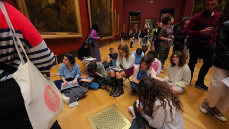 Gruppe-Von-Schülern,-Die-Auf-Dem-Boden-Des-Louvre-Museums-Sitzen-Und-Pariser-Geschichte-Lernen