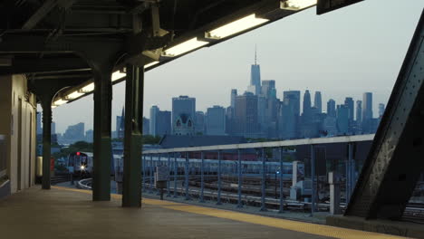 Metro-De-Nueva-York-En-Tren-Elevado-Entrando-A-La-Estación-Con-El-Horizonte-De-Manhattan-En-Segundo-Plano.