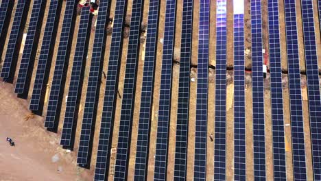 Aerial-drone-camera-moving-downwards-where-modules-are-being-fitted-to-solar-panels