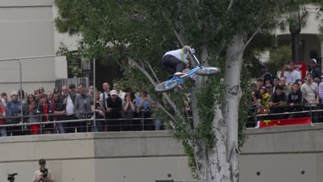 a-BMX-champion-doing-a-trick-with-his-blue-BMX,-in-slowmotion,-at-the-famous-FISE-in-Montpellier,-France,-with-spectators-in-the-background,-many-people-with-camera-to-shoot-him