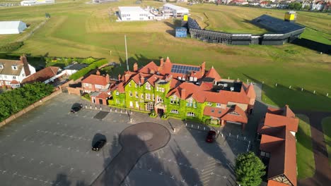Preparations-for-The-2023-Open-at-Royal-Liverpool-Golf-Club,-Wirral,-UK---Aerial-drone-clubhouse---slow-dronie,-course-and-area-reveal