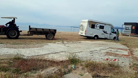 Tourist-campervan-stuck-in-sand-on-beach,-tractor-assists-in-vehicle-recovery
