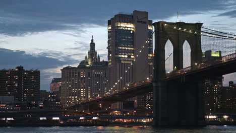 Vista-Crepuscular-Sobre-El-Río-Este-Del-Icónico-Puente-De-Brooklyn-Iluminado-En-Nueva-York,-Estados-Unidos
