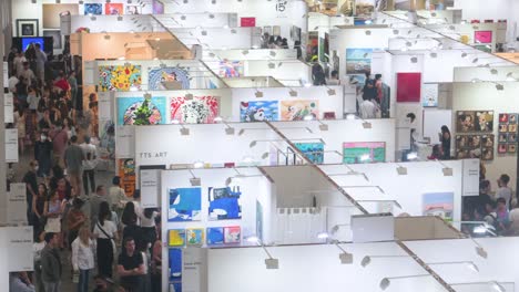 Overhead-shot-of-Chinese-visitors-attending-an-art-fair-show-where-art-exhibitors-sell-paintings-and-sculptures-to-visitors,-art-enthusiasts,-and-collectors