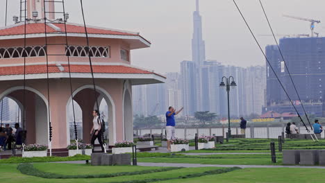 A-man-working-out-in-a-park-in-District-1,-Ho-Chi-Minh-City,-with-the-Landmark-81-building-and-river-in-the-background