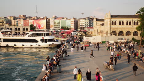 Walking-crowd-of-people-on-the-sunset-on-the-coast-of-Kadikoy-Square,-Istanbul,-and-the-Haldun-Taner-Theater-Building