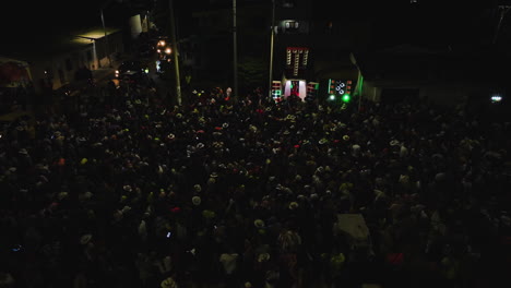 People-partying-the-Carnaval-Batalla-de-Flores,-on-night-streets-of-Barranquilla,-Colombia---Aerial-view