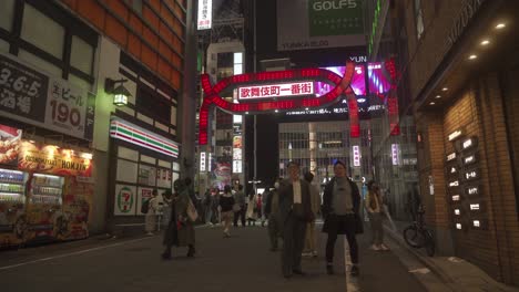 People-walking-at-night-through-Kabukicho-Japan's-main-red-light-district-in-Tokyo-neon-signs-and-nightlife