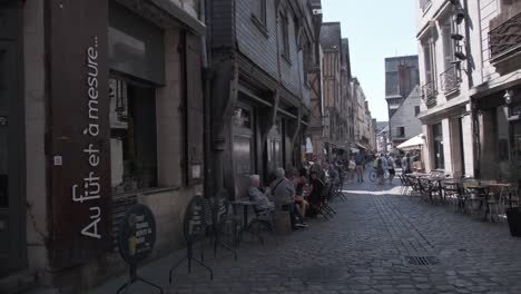 Walking-cobbled-narrow-street-in-Vieux-Tours-France,-with-cafes-busy-with-chatting-people-on-a-sunny-day