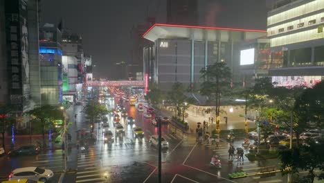 Aerial-establishing-shot-of-busy-traffic-on-road-in-downtown-of-Taipei-during-rainy-day-at-night---Pedestrian-with-um-fella-crossing-road-at-Christmas-time-in-Taiwan