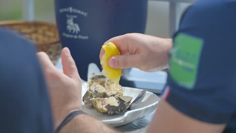 Hands-squeezing-lemon-over-an-oyster-on-a-plate