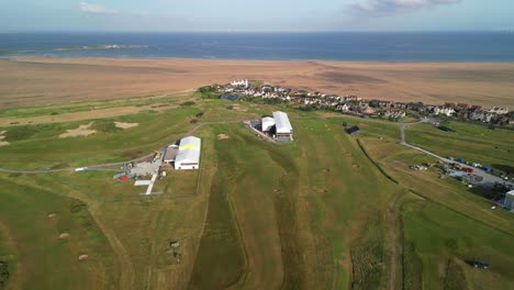 Preparations-for-The-2023-Open-at-Royal-Liverpool-Golf-Club,-Wirral,-UK---Aerial-drone-hospitality-tents-and-coastline,-reverse-and-reveal-course
