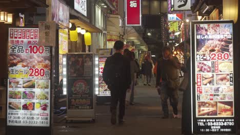 Locals-Walking-Along-Shinjuku-Street-Past-Restaurants-With-Menus-Being-Advertised-At-Night