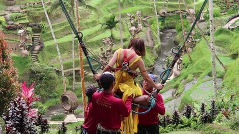 Staff-workers-of-Outdoor-Park-setting-up-Safety-Harness-for-a-woman-in-long-dress-on-a-swing-over-rice-fields-in-Alas-Harum-Bali