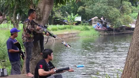 A-number-of-men-hunt-fish-on-the-edge-of-an-artificial-lake-in-Depok,-Indonesia