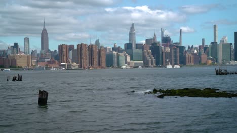Manhattan-skyline-from-Brooklyn,-East-River-with-waves-in-the-foreground,-looking-at-the-Empire-State-Building,-One-Vanderbilt,-and-midtown-Manhattan