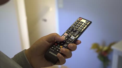 Afro-Hispanic-adult-woman-using-the-Tv-remote-in-the-living-room