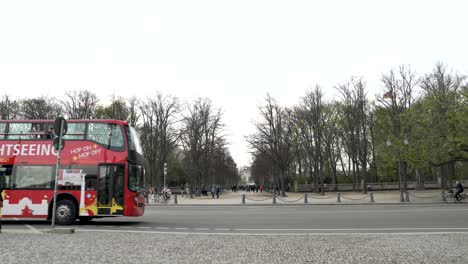 Red-Sightseeing-Double-decker-Bus-Driving-Past-Opposite-Sightseeing-Brandenburg-Gate-In-Berlin