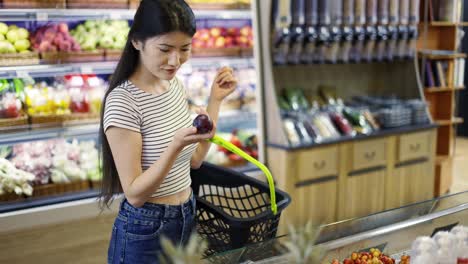 An-Asian-shop-visitor-chooses-fruits-and-vegetables-in-special-packages.-Hold-a-basket-in-your-hands