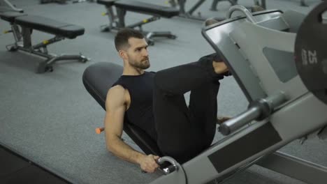 Muskulöser-Mann-Trainiert-An-Einem-Sporttrainingsgerät-Für-Die-Beinmuskulatur-Und-Hebt-Gewichte