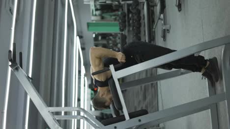 Male-bodybuilder-pushing-up-and-pulling-down-while-intensive-workout-in-fitness-club