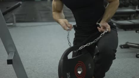 Strong-sportsman-holding-in-hands-steel-chain-and-weightlifting-belt-goes-to-hard-workout-at-gym
