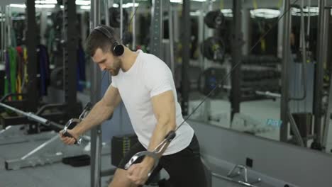 Bodybuilder-guy-in-gym-pumping-up-hands-close-up-in-headphones