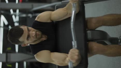 Muskulöser-Bodybuilder-Beim-Gewichtheben-Im-Fitnessstudio-Auf-Einem-Stuhl