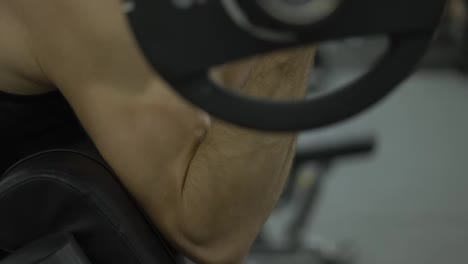 Close-up-of-man's-biceps-doing-weight-lifting-in-gym-on-bench