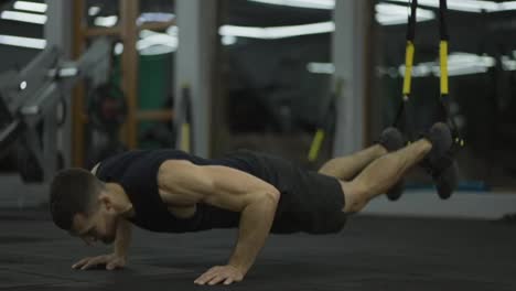 Sportsman-doing-flooring-abs-exercises-with-TRX-straps-at-gym