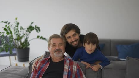 Portrait-of-happy-caucasian-three-generation-men-smiling-to-the-camera-at-home,-front-view