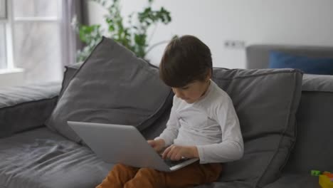 Kleiner-Süßer-Junge-Benutzt-Einen-Laptop,-Der-Auf-Dem-Sofa-Sitzt