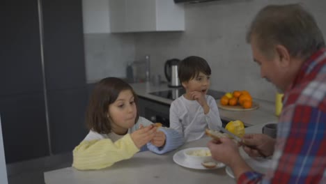 Dos-Niños-Pequeños-Están-Comiendo-Sándwiches-Hechos-Por-El-Abuelo