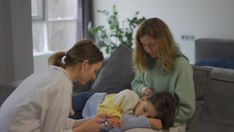 Doctor-examines-little-girl-checks-oxygen-level-on-mom's-knees