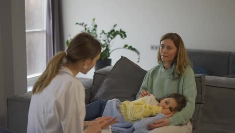 Madre-Con-Una-Hija-Pequeña-Hablando-Con-Un-Visitante-De-Salud-En-Casa