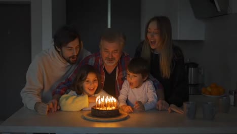 Abuelo-Feliz-Soplando-Velas-En-El-Pastel-De-Cumpleaños-Junto-Con-Su-Gran-Familia
