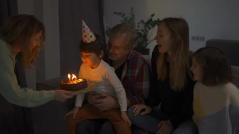 Little-boy-blows-out-the-candles-on-dream-the-cake-in-a-circle-of-happy-family